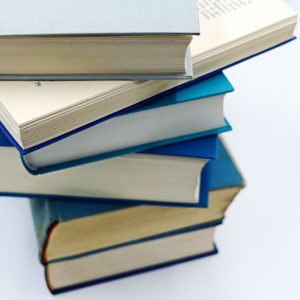 A pile of books with blue covers on a white background, symbolizing education and knowledge.